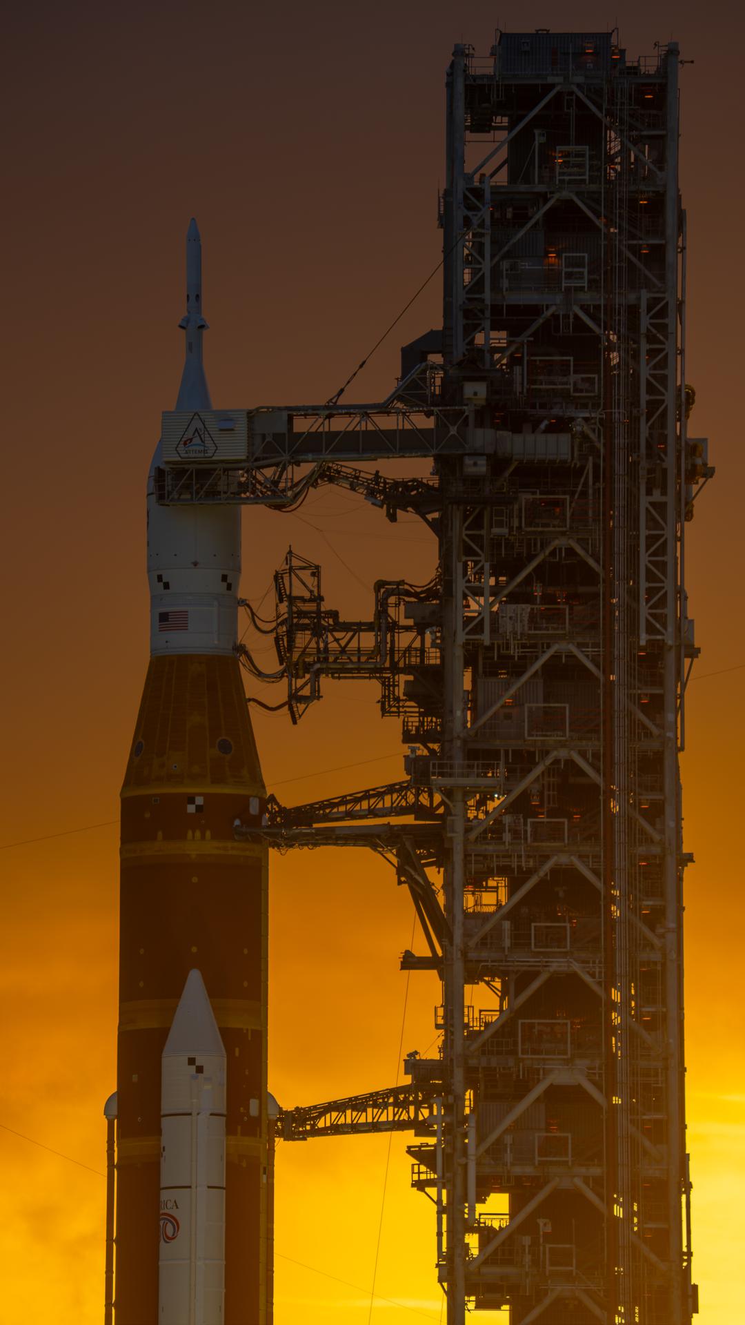This image shows a sunset of NASA’s SLS (Space Launch System) and Orion spacecraft at NASA’s Kennedy Space Center. NASA's massive Crawler-Transporter, upgraded for the Artemis program, carried the powerful SLS rocket and Orion spacecraft on the Mobile Launcher from the Vehicle Assembly Building to Launch Pad 39B at Kennedy Space Center in preparation for the Artemis II mission.